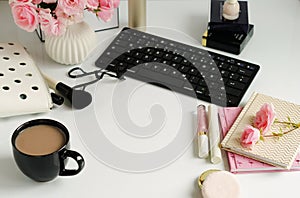 Female make up accessories, cup of cofee and bouquet of pink roses on white background. Flat lay, top view feminine desk, workspac