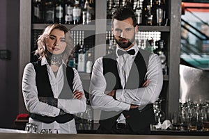 female and male bartenders standing with crossed arms