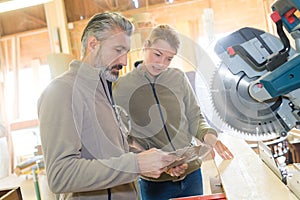 female and male carpenters cutting wooden plank