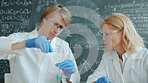Female and male chemists working in lab with test tubes busy with experiment