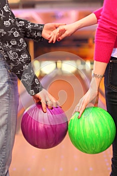 Female and male hands with balls in bowling club