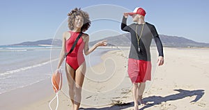 Female and male lifeguards walking along beach