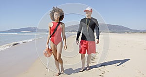 Female and male lifeguards walking along beach