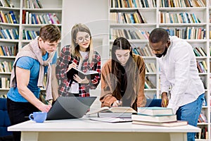 Female and male multiethnic students study in the college library. Learning and preparing for exam. Education concept.