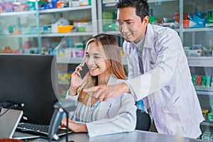 female and male pharmacists receiving phone calls while serving consultations