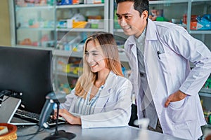 female and male pharmacists in uniform looking at monitor together