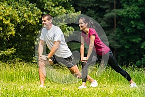 Female and male runner stretching outdoors