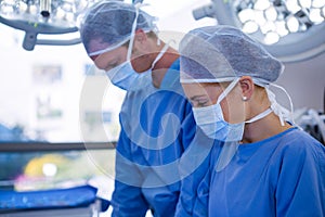 Female and male surgeon wearing surgical mask in operation theater