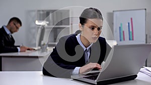 Female manager attentively reading documents on laptop, searching for mistake