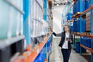 Female manager checking stocks while using digital tablet in warehouse