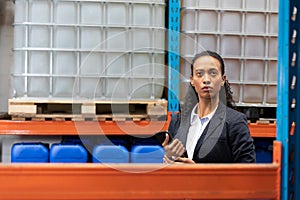 Female manager checking stocks while using digital tablet in warehouse