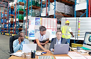 Female manager with her coworker discussing over laptop at desk