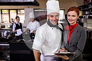 Female manager and male chef writing on clipboard in kitchen