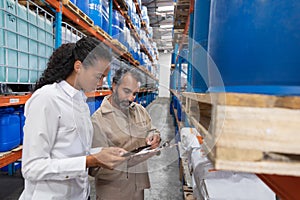 Female manager and male staff discussing over clipboard in warehouse