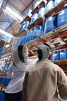 Female manager and male staff interacting with each other while checking stocks in warehouse