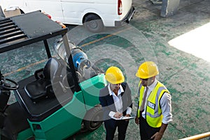 Female manager and male supervisor discussing over clipboard in warehouse