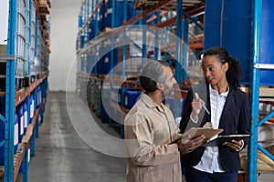 Female manager and male worker discussing over clipboard in warehouse