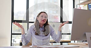 Female manager shrugs shoulders in confusion at workplace