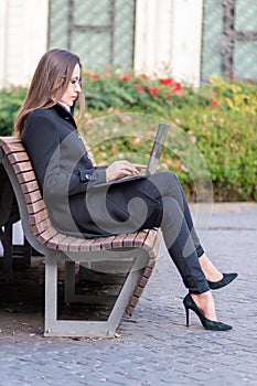 Female manager sitting on a bench, with computer and telephone