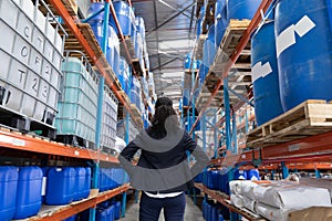 Female manager standing with hands folded in warehouse