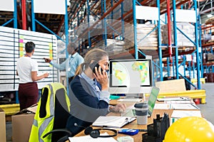 Female manager talking on mobile phone at desk