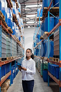 Female manager using digital tablet while checking stocks in warehouse