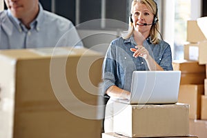 Female Manager Using Headset In Distribution Warehouse