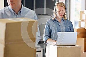 Female Manager Using Headset In Distribution Warehouse