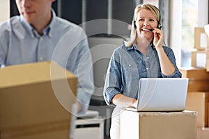 Female Manager Using Headset In Distribution Warehouse