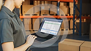Female Manager Using Laptop Computer To Check Inventory. In the Background Warehouse Retail Center