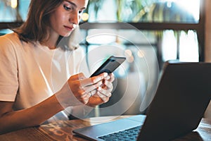 Female manager using smartphone in cafe, young hipster girl freelancer writing on mobile phone, businesswoman working via portable