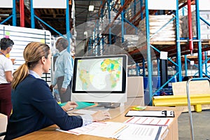 Female manager working on computer at desk in warehouse