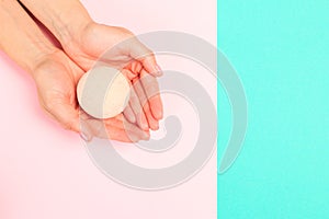 Female  manicure. Beautiful young woman`s hands holding a bathroom bomb on pastel background