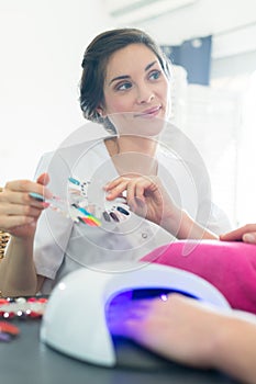 Female manicurist showing choices for nail extension