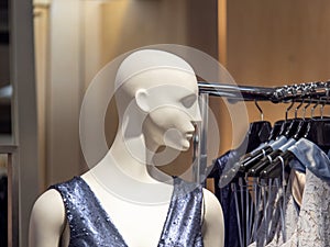 Female mannequin in dress next to clothing rack in department store display