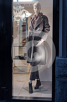 Female mannequin with luxury clothes in shop window showcase of store mall market.