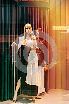 Female mannequin in shop window showcase of store mall market. Fashion clothes - dress, jacket. Mannequins dressed in