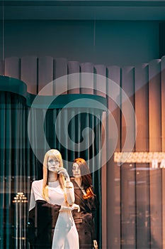 Female mannequin in shop window showcase of store mall market. Fashion clothes - dress, jacket. Mannequins dressed in