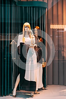 Female mannequin in shop window showcase of store mall market. Fashion clothes - dress, jacket. Mannequins dressed in