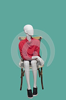 Female mannequin sitting on chair