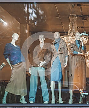 Female mannequins in shop window with demi-season clothing, street reflection. Shopping