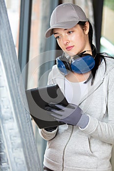 female manual worker with ear defenders using digital tablet