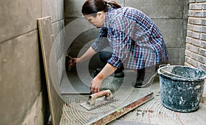 Female manual worker laying a new tile floor