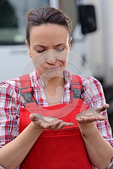 Female manual worker looking woefully at dirty hands