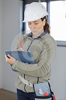 female manual worker making notes on clipboard