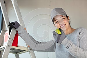 female manual worker by stepladder holds apple