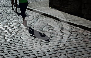 Female marathon runner and her shadow on city cobblestoned street