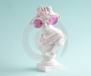 Female marble statue in large pink glasses on  blue background. Concept of  positive view  and lies