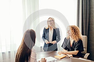 Marketing experts sit around table and looking at woman speaker at meeting.