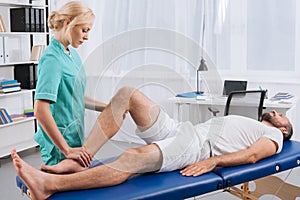 female massage therapist doing leg massage to patient on massage table